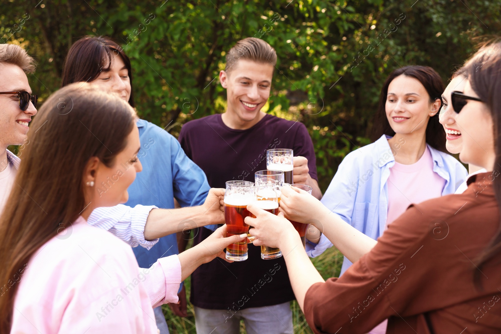 Photo of Group of happy friends clinking glasses of beer outdoors