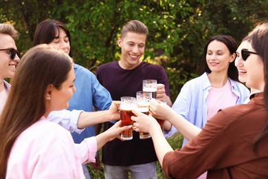 Photo of Group of happy friends clinking glasses of beer outdoors