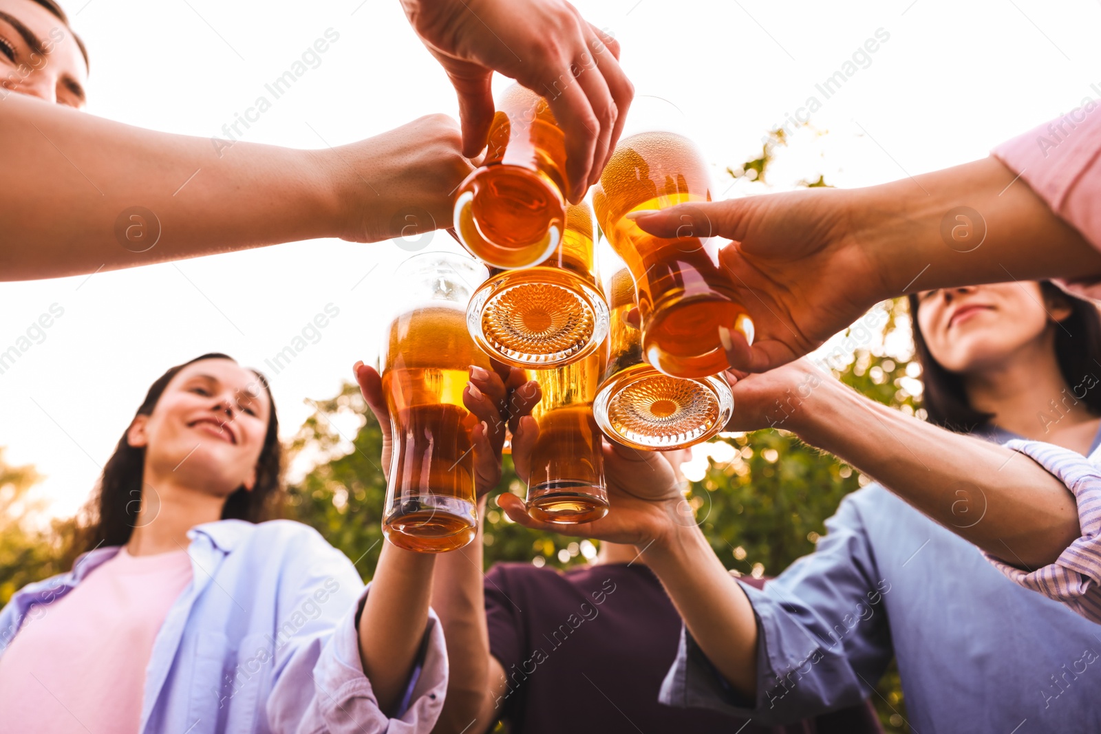 Photo of Group of happy friends clinking glasses of beer outdoors, bottom view