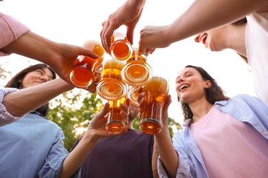 Photo of Group of happy friends clinking glasses of beer outdoors, bottom view