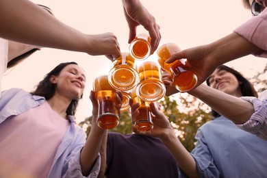 Photo of Group of happy friends clinking glasses of beer outdoors, bottom view
