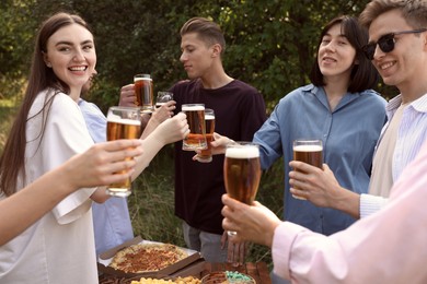 Photo of Group of happy friends clinking glasses of beer outdoors
