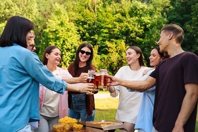 Photo of Group of happy friends clinking glasses of beer outdoors
