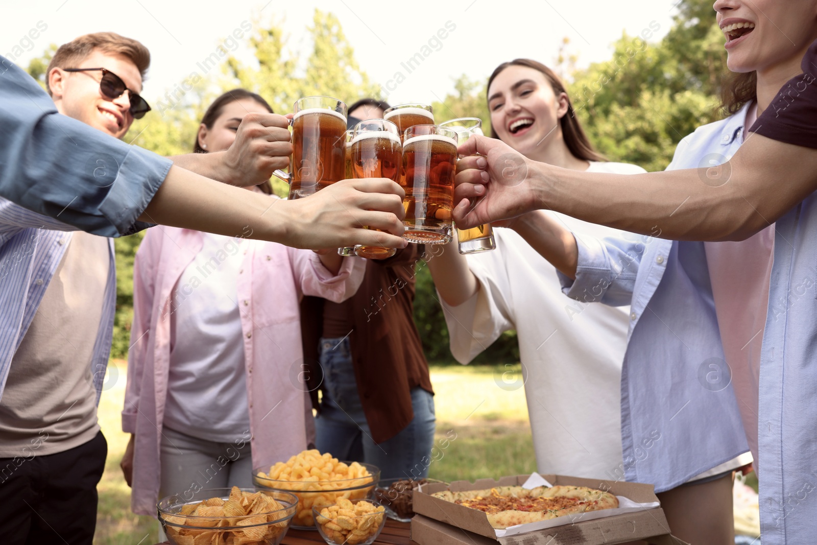 Photo of Group of happy friends clinking glasses of beer outdoors