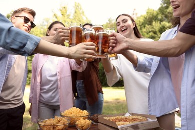 Photo of Group of happy friends clinking glasses of beer outdoors