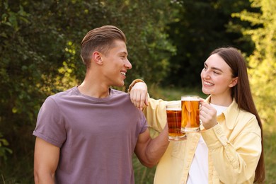 Photo of Young man and woman with glasses of beer having fun outdoors