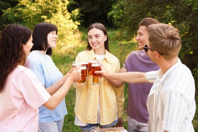 Photo of Group of happy friends clinking glasses of beer outdoors