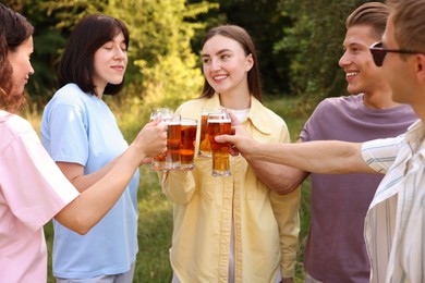 Photo of Group of happy friends clinking glasses of beer outdoors