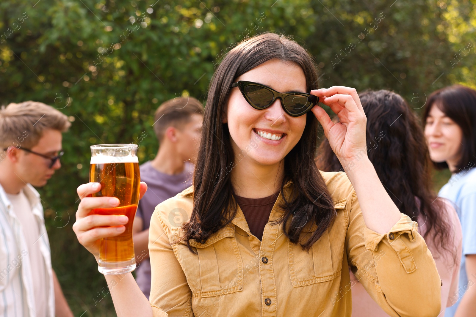 Photo of Group of happy friends having fun and drinking beer outdoors, selective focus