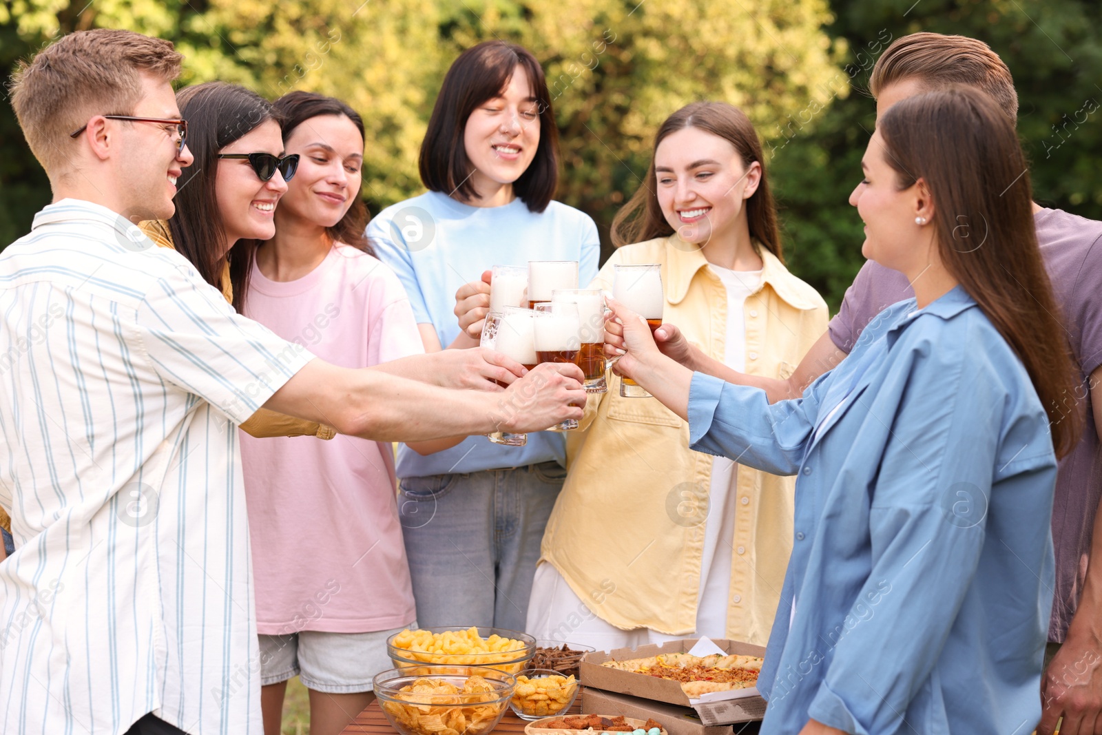 Photo of Group of happy friends clinking glasses of beer outdoors