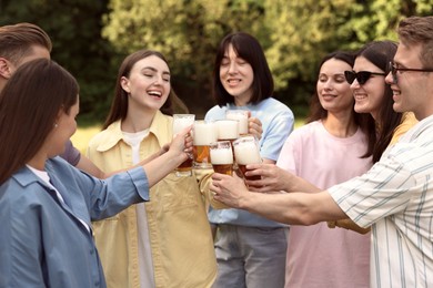 Photo of Group of happy friends clinking glasses of beer outdoors