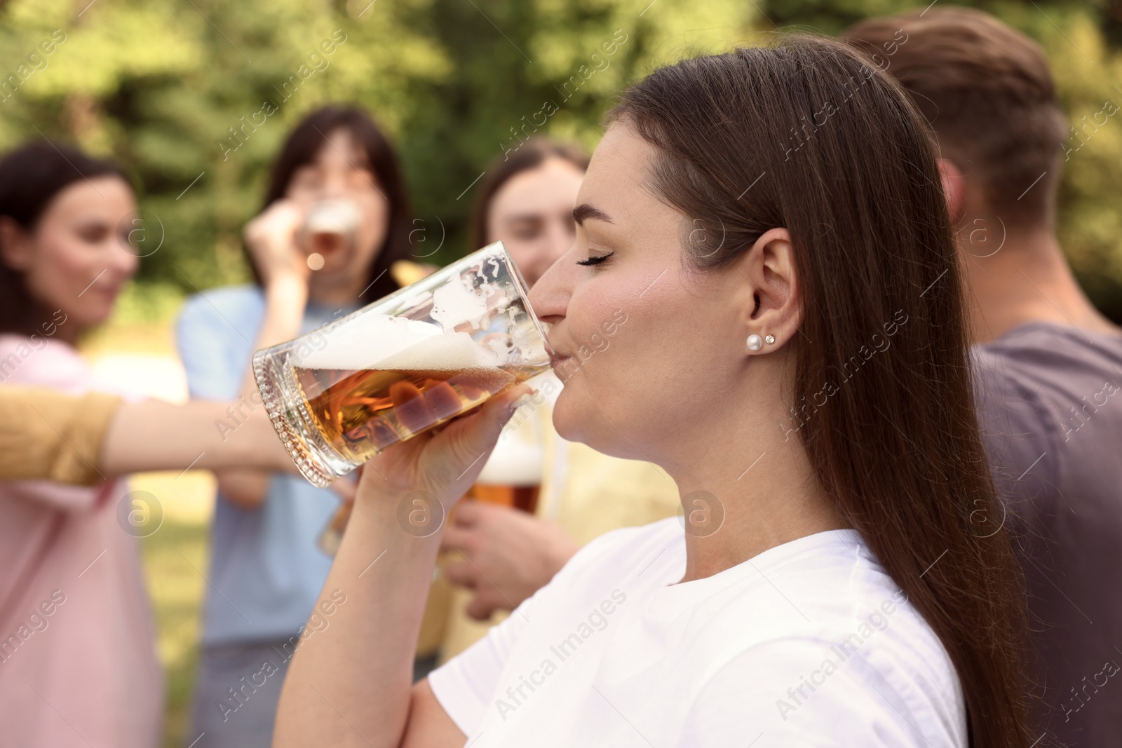 Photo of Group of happy friends having fun and drinking beer outdoors, selective focus