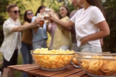 Photo of Group of happy friends having fun and drinking beer outdoors, focus on snacks