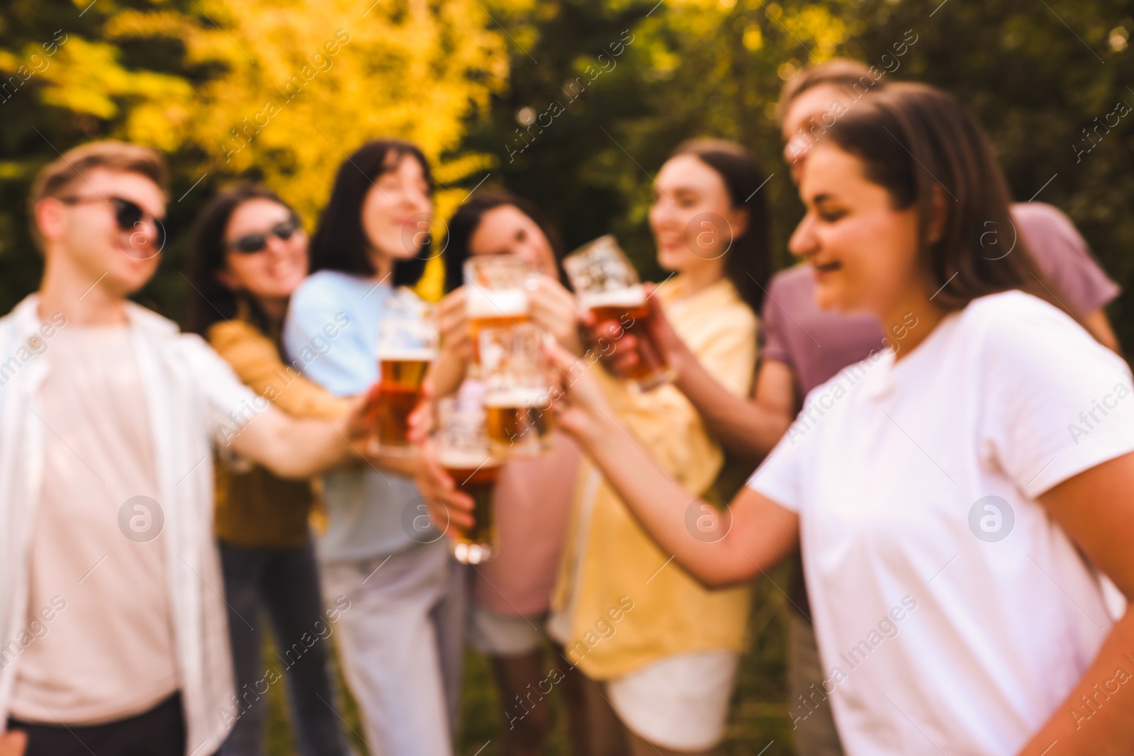 Photo of Blurred view of happy friends having fun and drinking beer outdoors