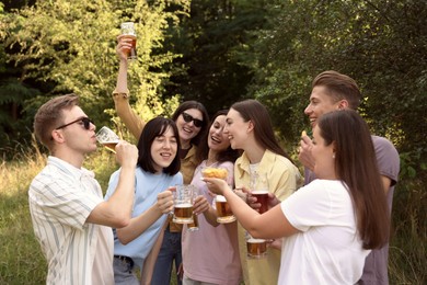 Photo of Group of happy friends clinking glasses of beer outdoors