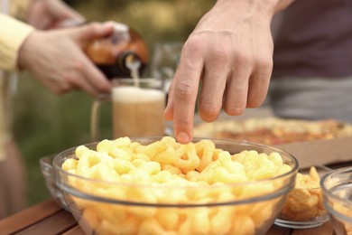 Photo of Group of friends eating snacks and drinking beer outdoors, closeup