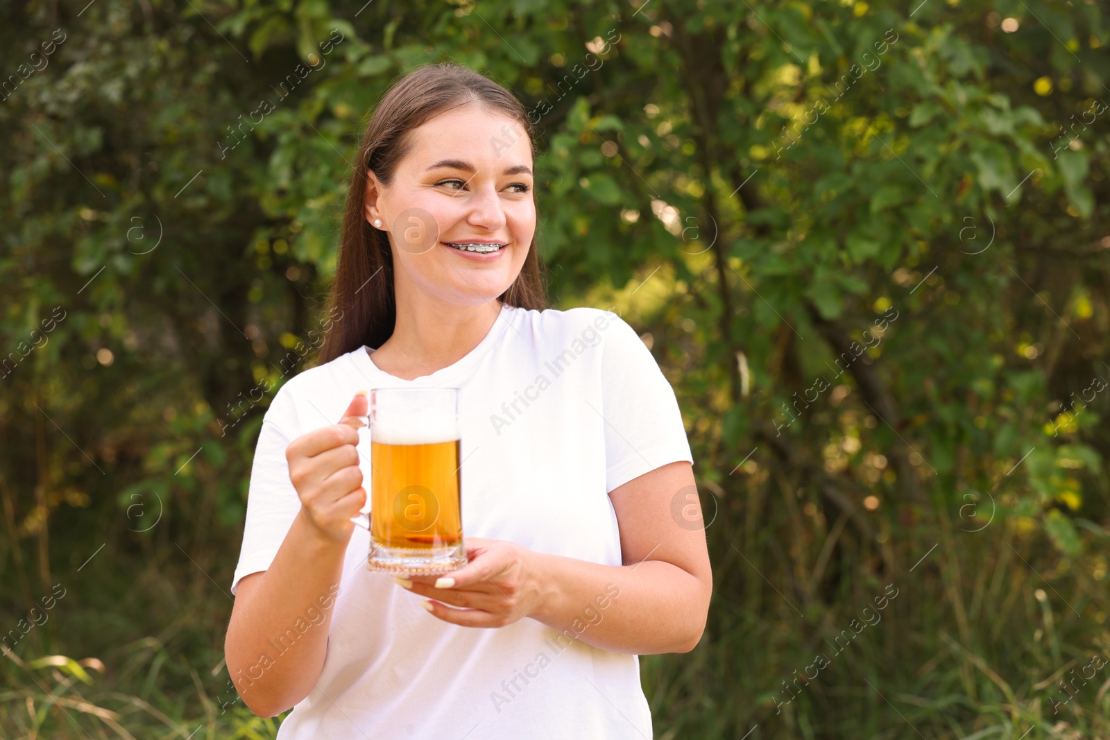 Photo of Young woman with glass of beer outdoors, space for text