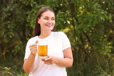 Photo of Young woman with glass of beer outdoors, space for text