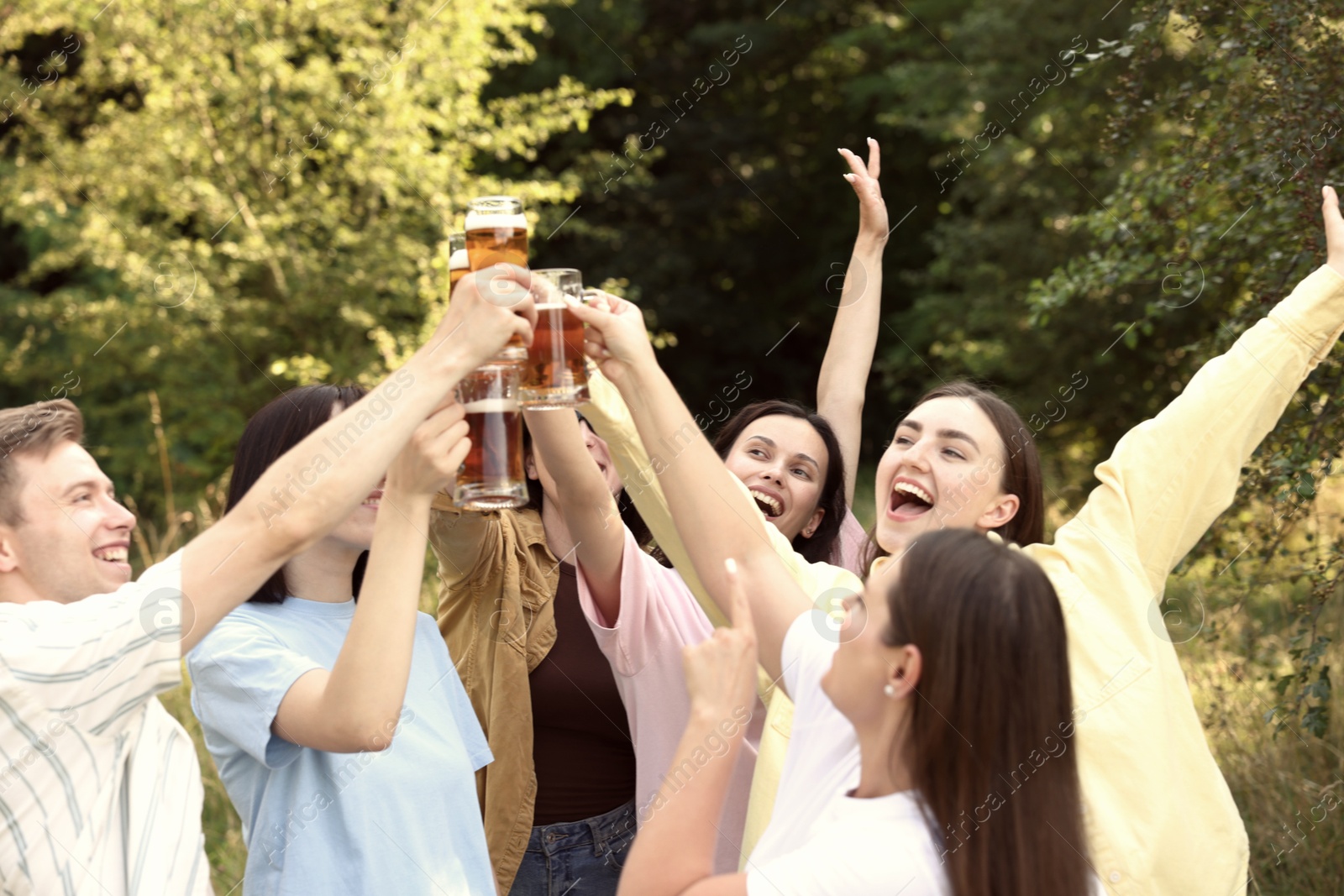 Photo of Group of happy friends clinking glasses of beer outdoors