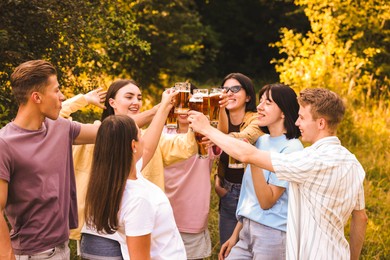 Photo of Group of happy friends clinking glasses of beer outdoors