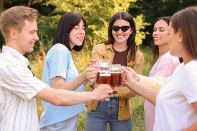 Photo of Group of happy friends clinking glasses of beer outdoors