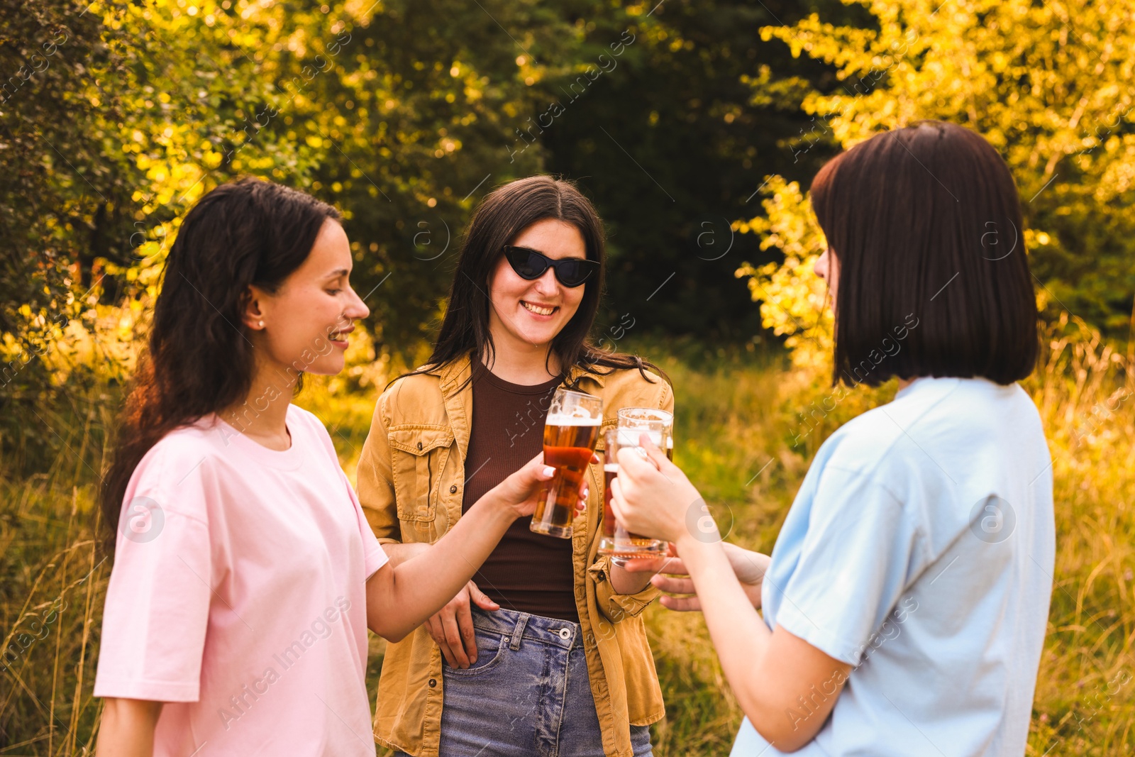 Photo of Group of happy friends clinking glasses of beer outdoors
