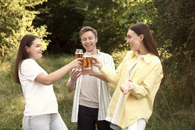 Photo of Group of happy friends clinking glasses of beer outdoors