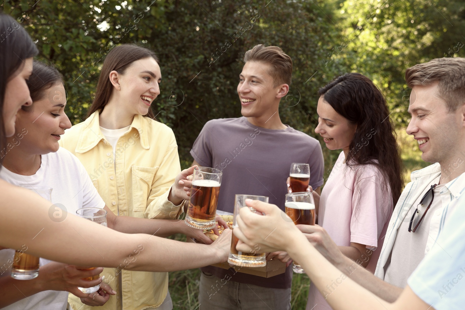 Photo of Group of happy friends with pizza having fun and drinking beer outdoors
