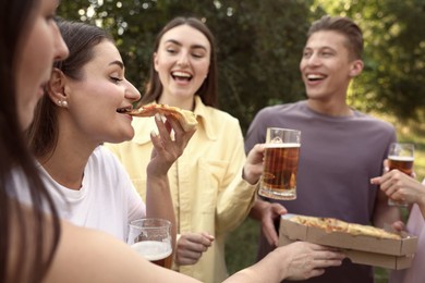 Photo of Group of happy friends with pizza having fun and drinking beer outdoors, selective focus