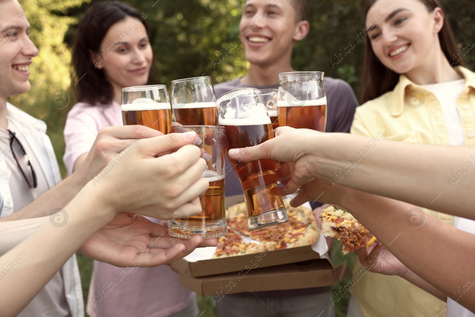 Group of happy friends with pizza clinking glasses of beer outdoors, selective focus Photo of Group of happy friends with pizza clinking glasses of beer outdoors, selective focus