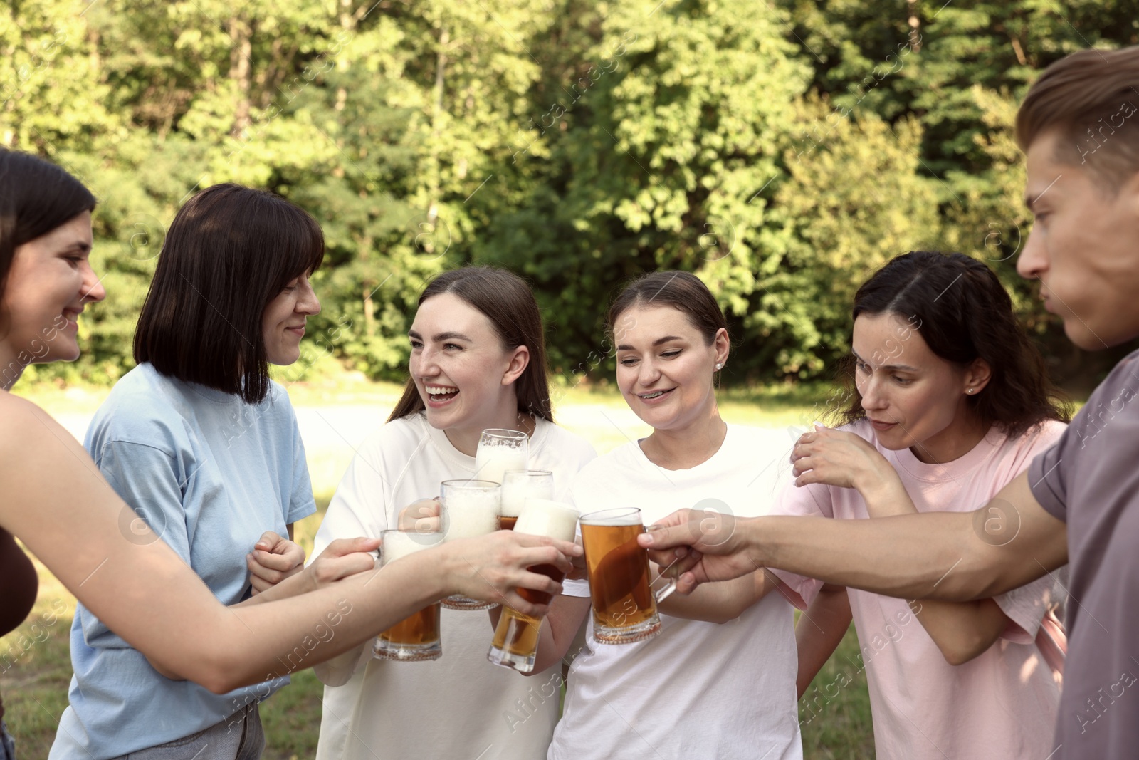 Photo of Group of happy friends clinking glasses of beer outdoors