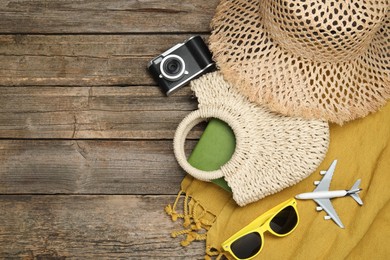 Photo of Time for summer vacation. Beach accessories, camera, toy plane and sunglasses on wooden background, flat lay. Space for text