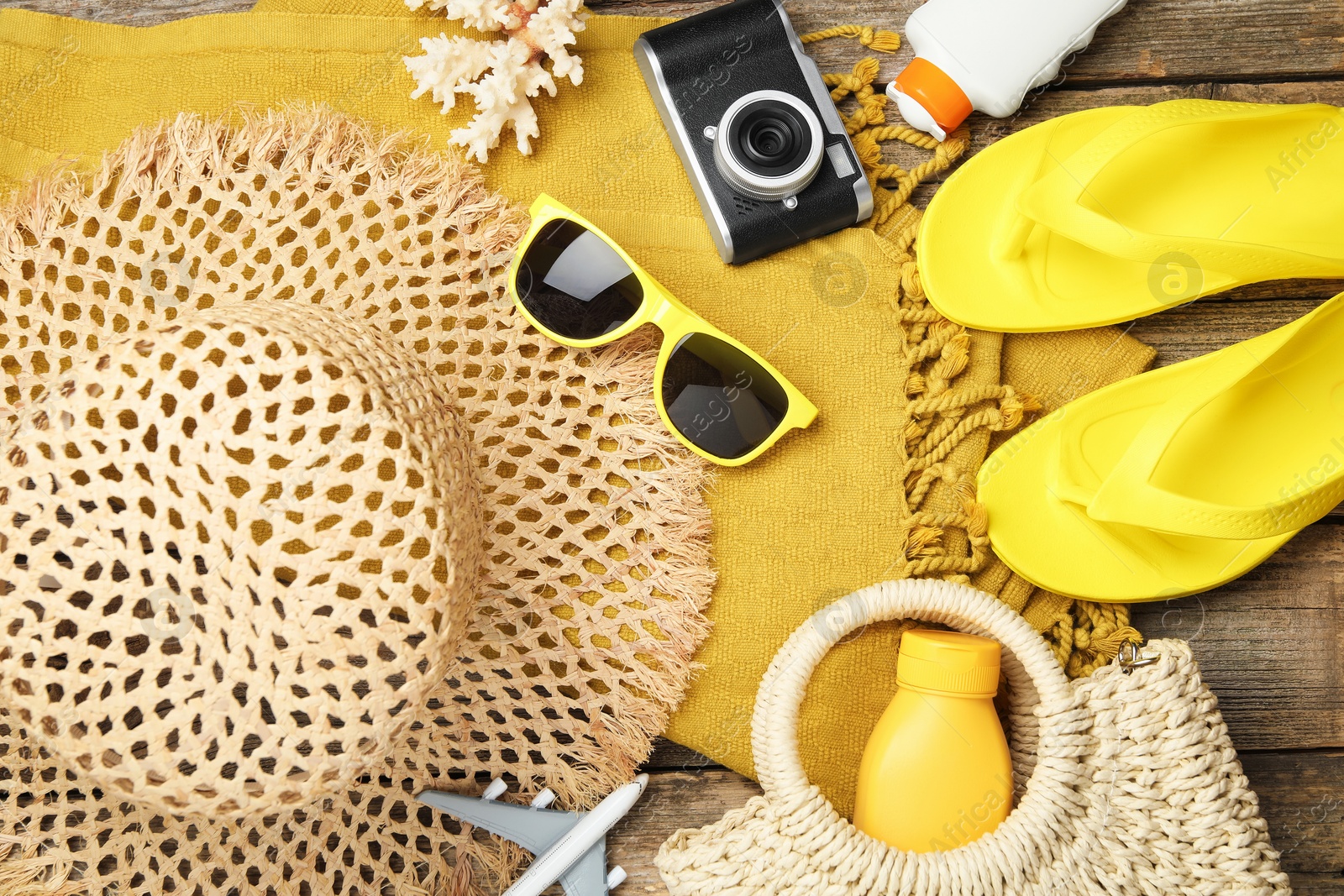 Photo of Beach accessories, camera and toy plane on wooden background, flat lay. Time for summer vacation