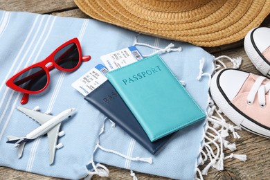 Photo of Passports, flight tickets, toy plane, shoes and beach accessories on wooden background, closeup. Time for summer vacation