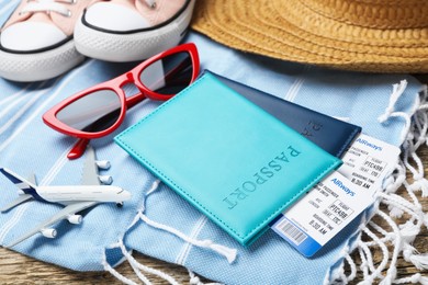 Photo of Passports, flight tickets, toy plane, shoes and beach accessories on wooden background, closeup. Time for summer vacation