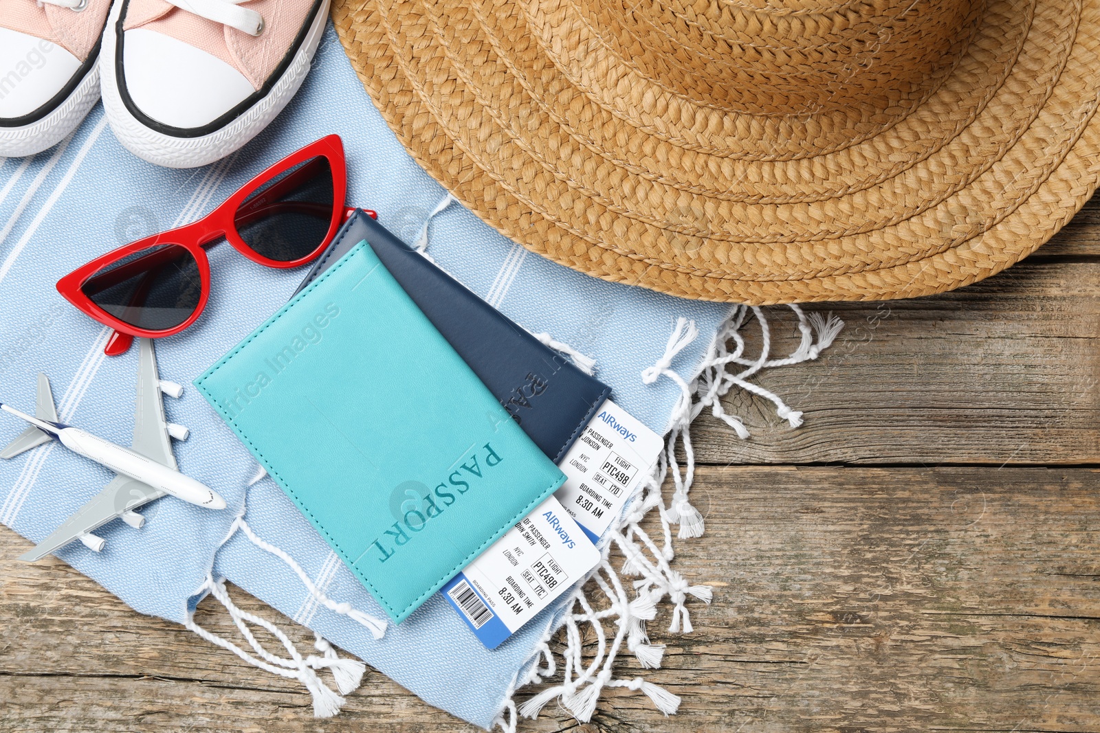 Photo of Passports, flight tickets, toy plane, shoes and beach accessories on wooden background, flat lay. Time for summer vacation