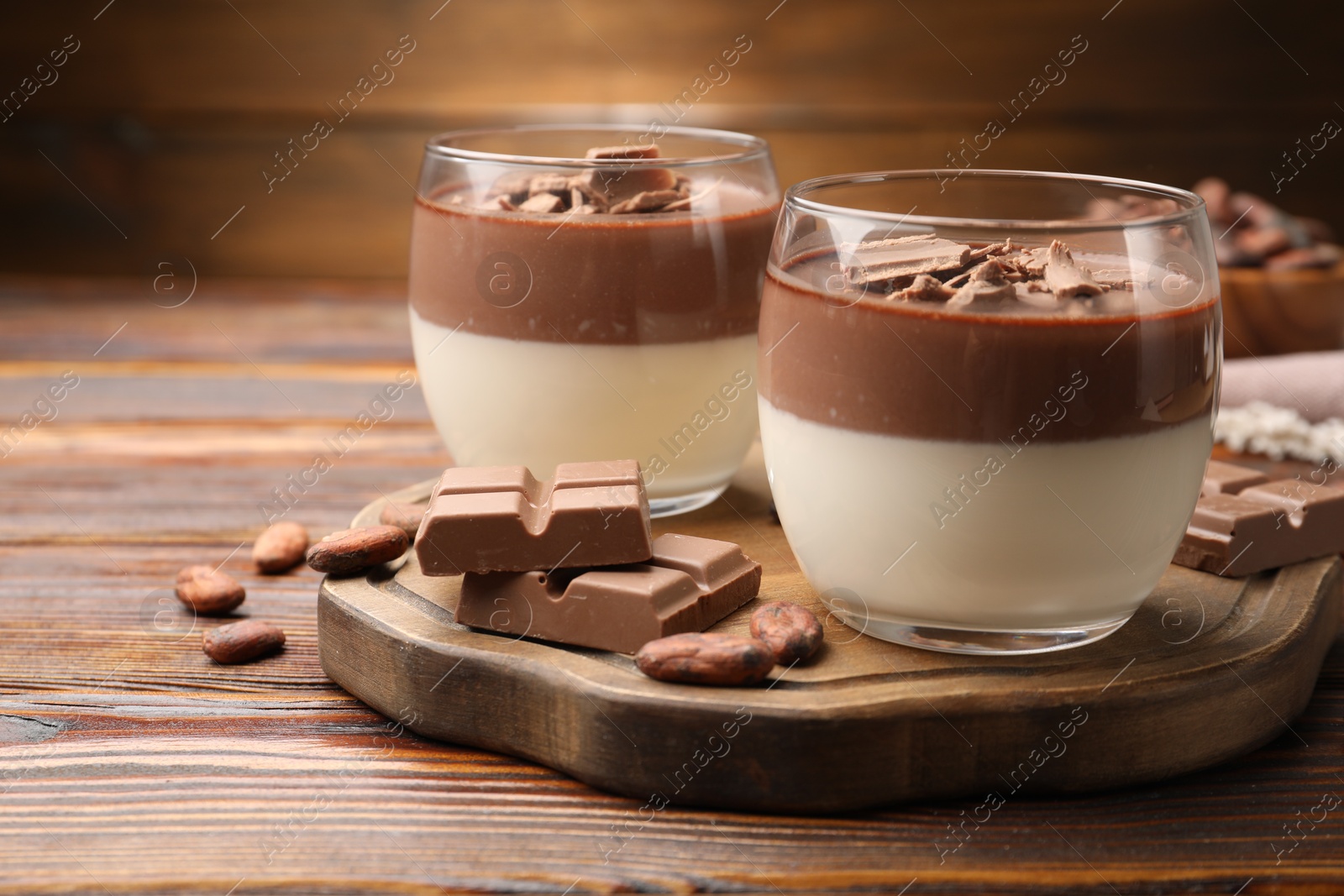 Photo of Delicious panna cotta with chocolate and cocoa beans on wooden table, closeup