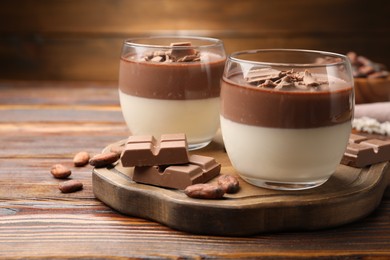 Photo of Delicious panna cotta with chocolate and cocoa beans on wooden table, closeup