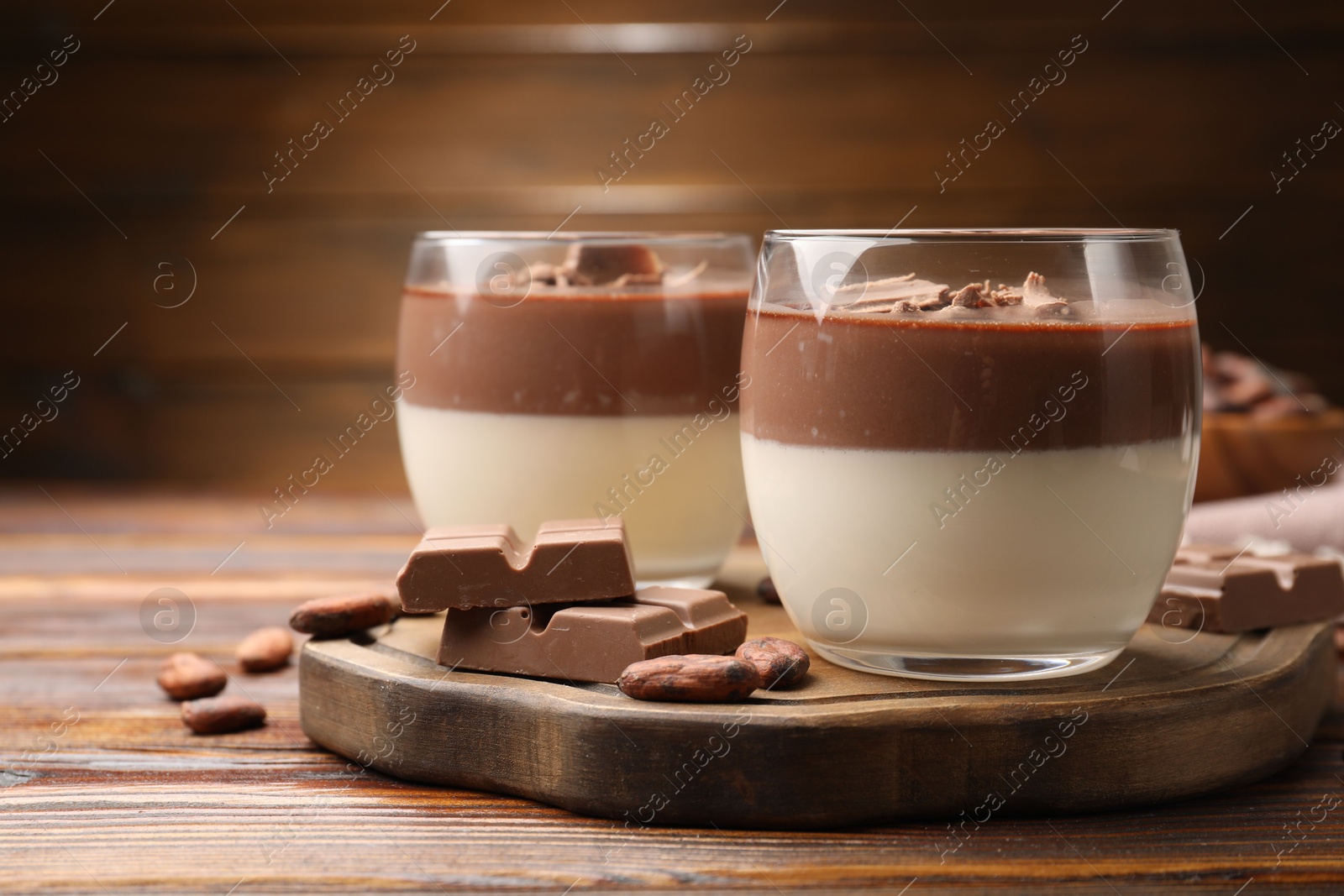 Photo of Delicious panna cotta with chocolate and cocoa beans on wooden table, closeup