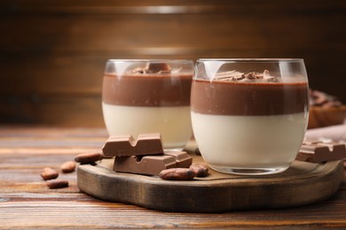 Photo of Delicious panna cotta with chocolate and cocoa beans on wooden table, closeup