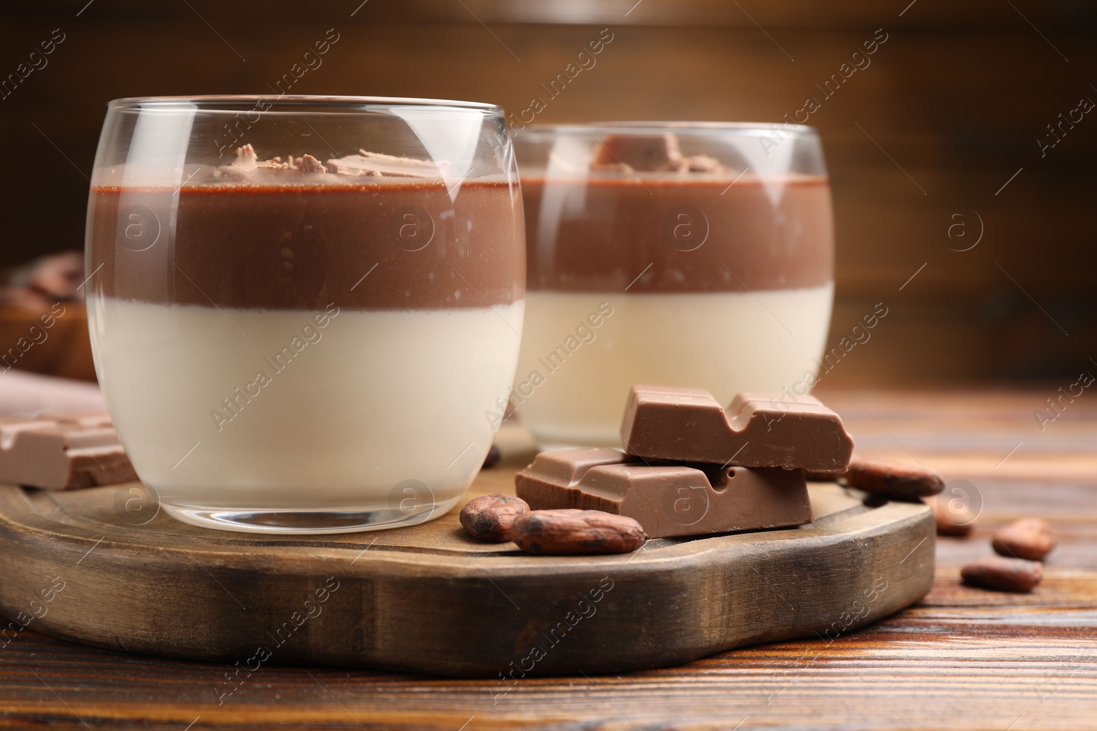 Photo of Delicious panna cotta with chocolate and cocoa beans on wooden table, closeup