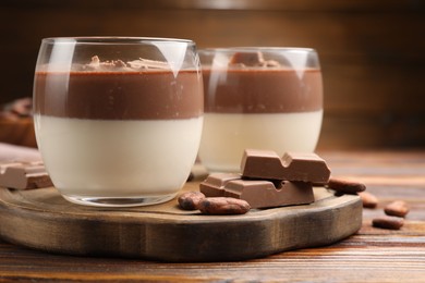 Photo of Delicious panna cotta with chocolate and cocoa beans on wooden table, closeup
