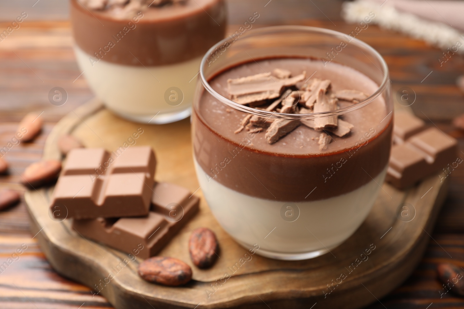 Photo of Delicious panna cotta with chocolate and cocoa beans on wooden table, closeup