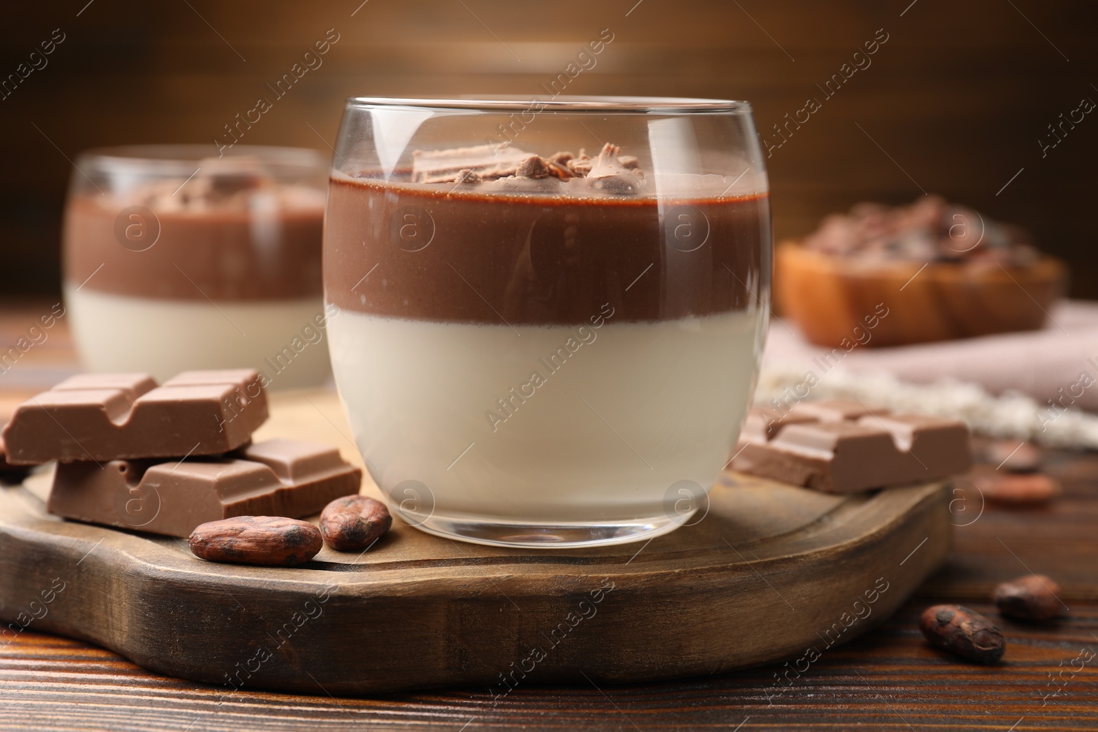 Photo of Delicious panna cotta with chocolate and cocoa beans on wooden table, closeup