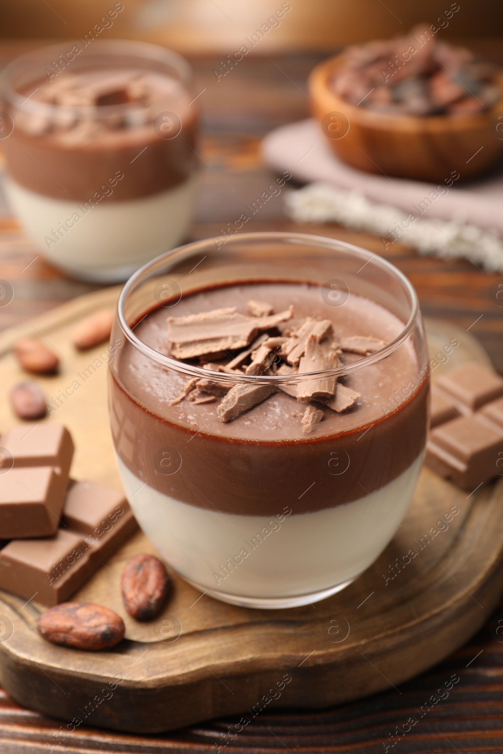 Photo of Delicious panna cotta with chocolate and cocoa beans on wooden table, closeup