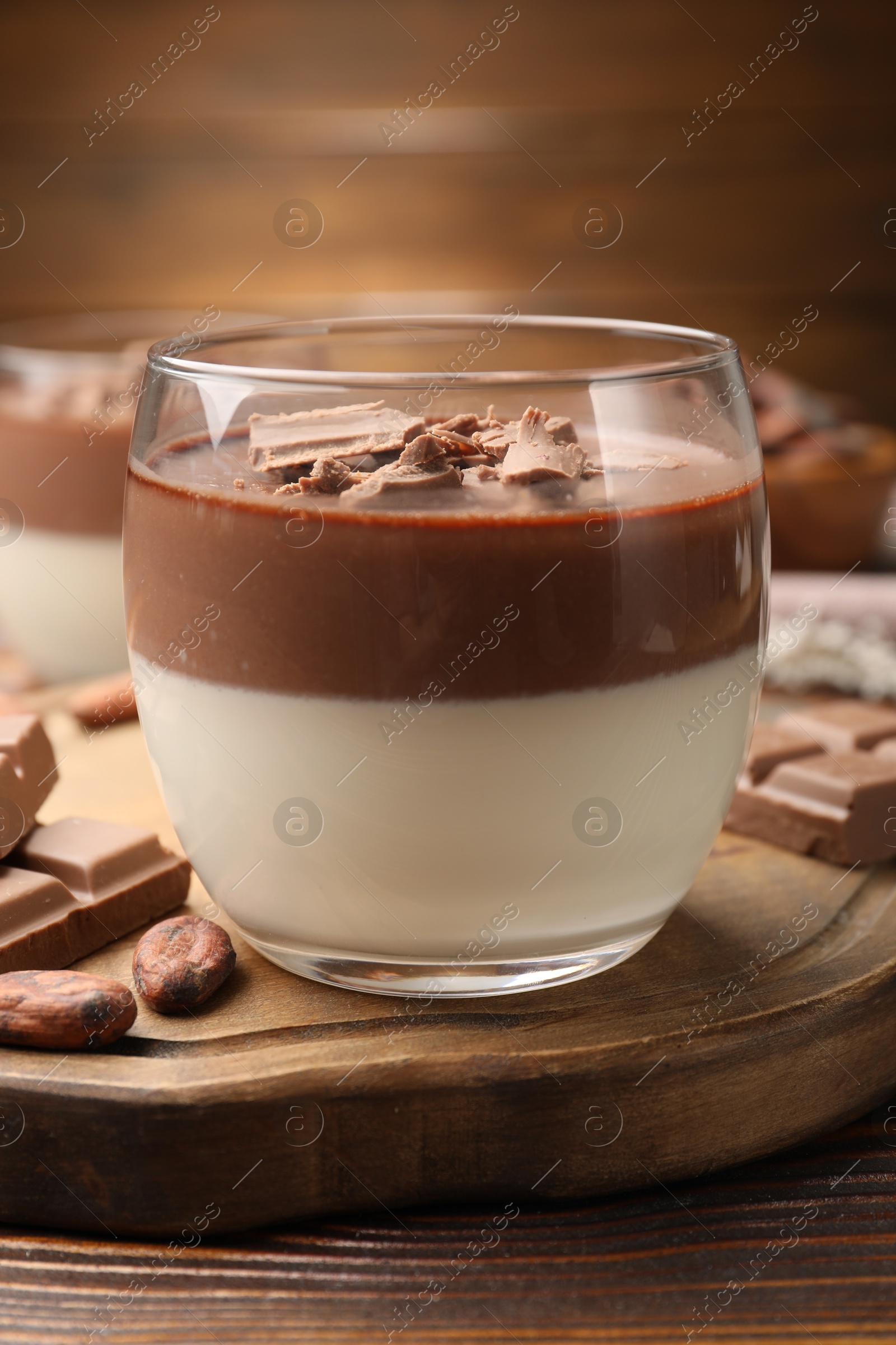 Photo of Delicious panna cotta with chocolate and cocoa beans on wooden table, closeup