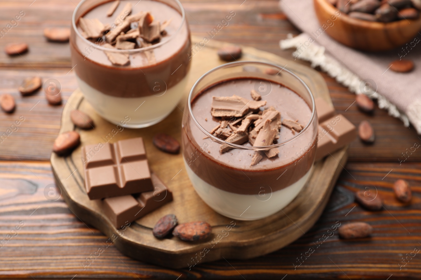 Photo of Delicious panna cotta with chocolate and cocoa beans on wooden table, closeup