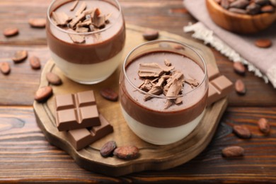 Photo of Delicious panna cotta with chocolate and cocoa beans on wooden table, closeup