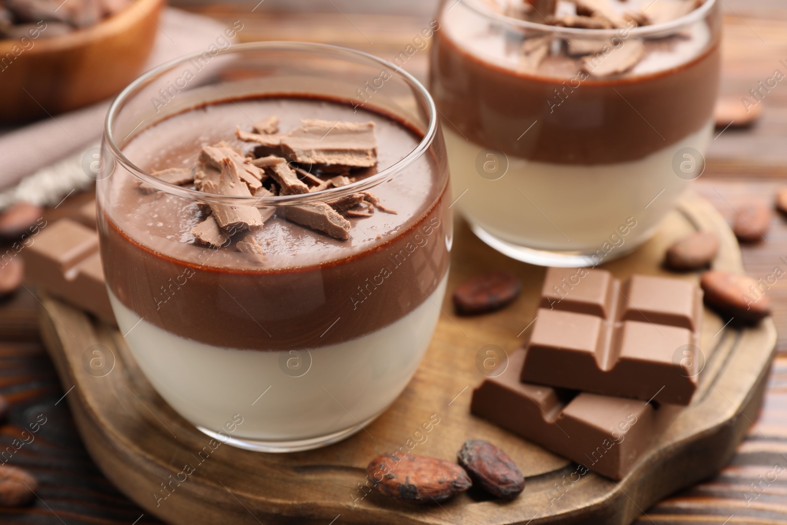 Photo of Delicious panna cotta with chocolate and cocoa beans on wooden table, closeup
