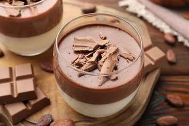 Photo of Delicious panna cotta with chocolate and cocoa beans on wooden table, closeup
